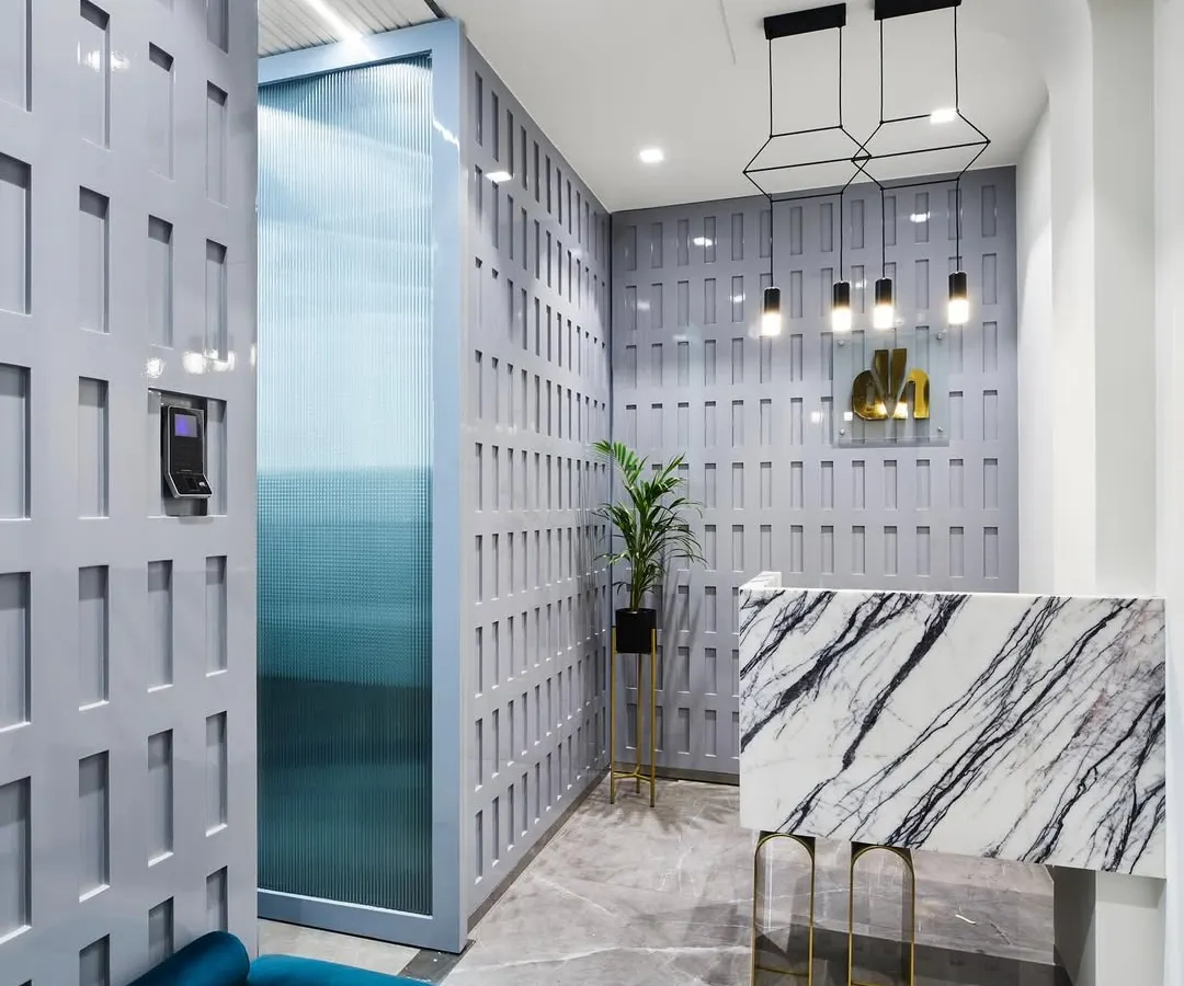 A first impression matters. This reception area for the 'Greywood Loft' project was designed to be unforgettable, featuring a statement marble desk, custom geometric wall paneling, and dramatic pendant lighting.