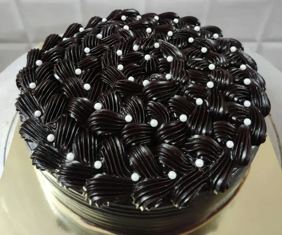 I love the challenge of creating detailed frosting designs. This rich chocolate cake features an intricate basket-weave piping technique, with each swirl carefully placed and dotted with delicate white pearls for an elegant finish.