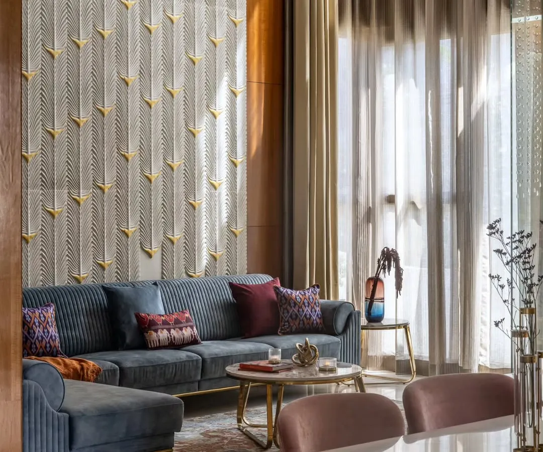 In the living area of the Avani Residence, sunlight streams through double-height windows, illuminating a custom-carved stone panel inspired by peacock feathers. This space is a testament to our philosophy of using light as a key design element to create evolving, artistic interiors.