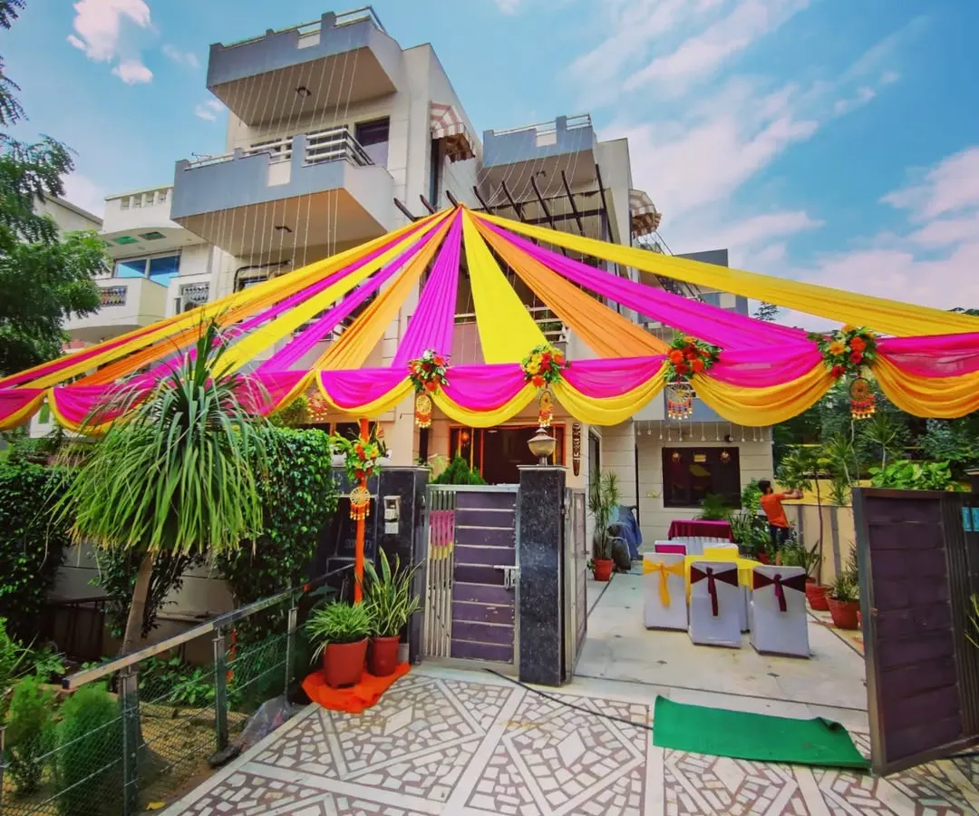 For home-based functions like a Mehandi or Sangeet, I transform the entire front of the house. Here you can see a full canopy of bright pink and yellow fabric drapes, creating a festive atmosphere right from the street.