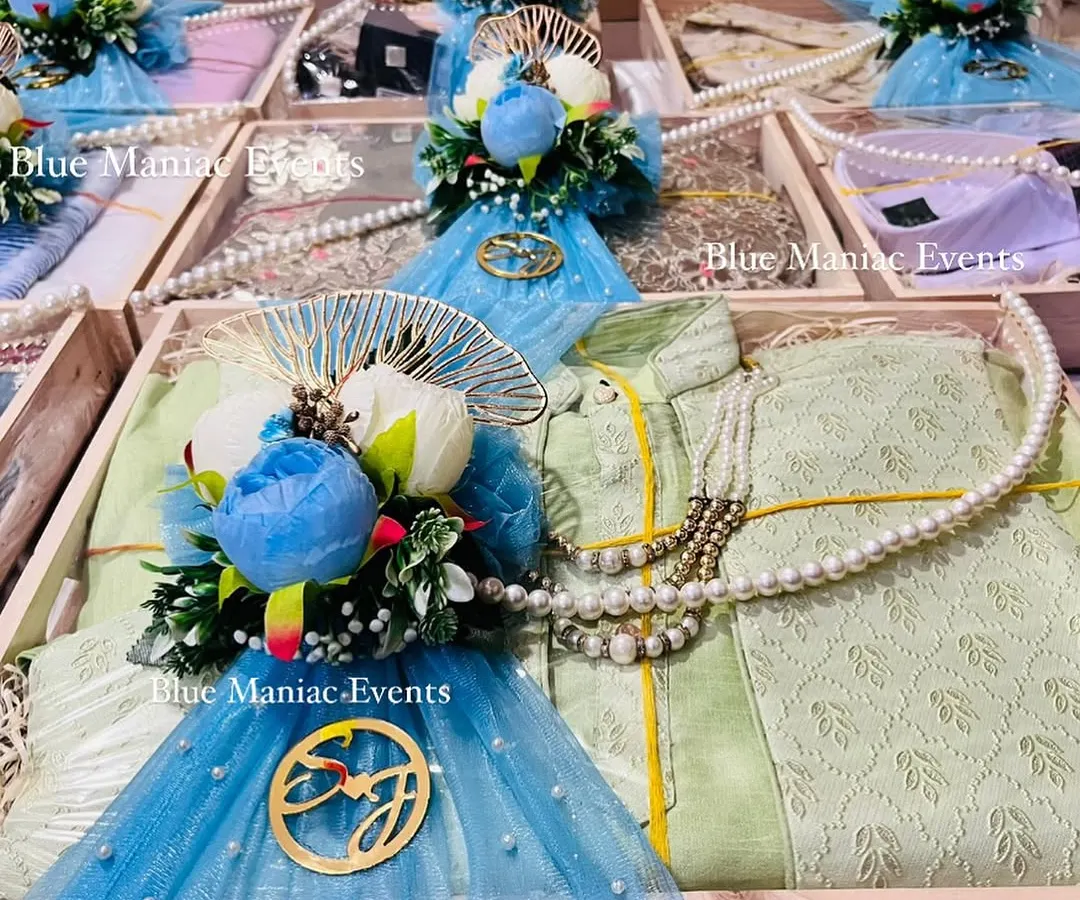 Detail is key. This close-up shows the custom golden acrylic monogram with the couple's initials, set against sheer blue net with scattered pearl details. These personal touches make your trousseau truly unique.