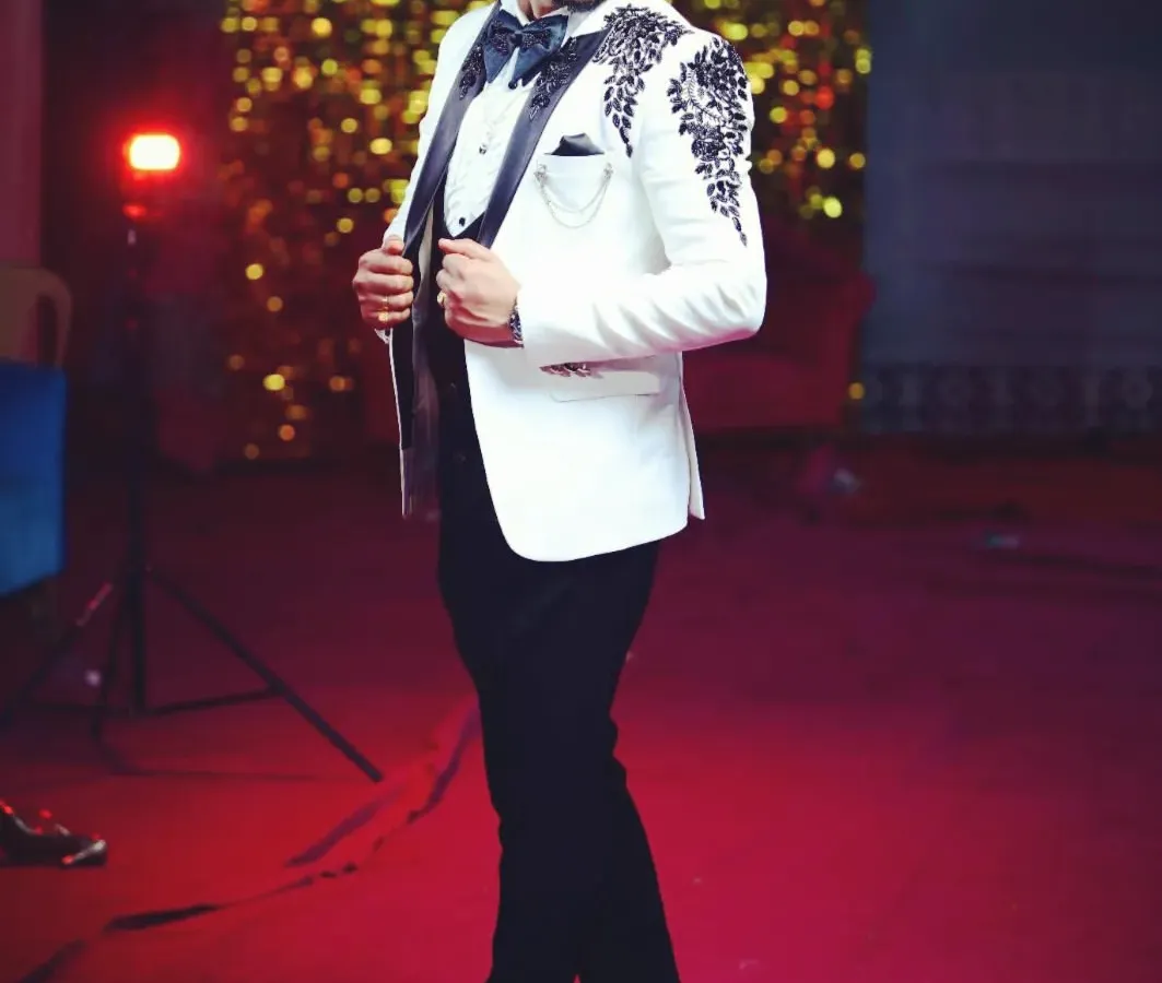 Look sharp and confident at your reception or cocktail event. This client is wearing a custom-tailored white tuxedo jacket with a modern three-piece construction, detailed with unique black embroidery on the lapels and shoulders.