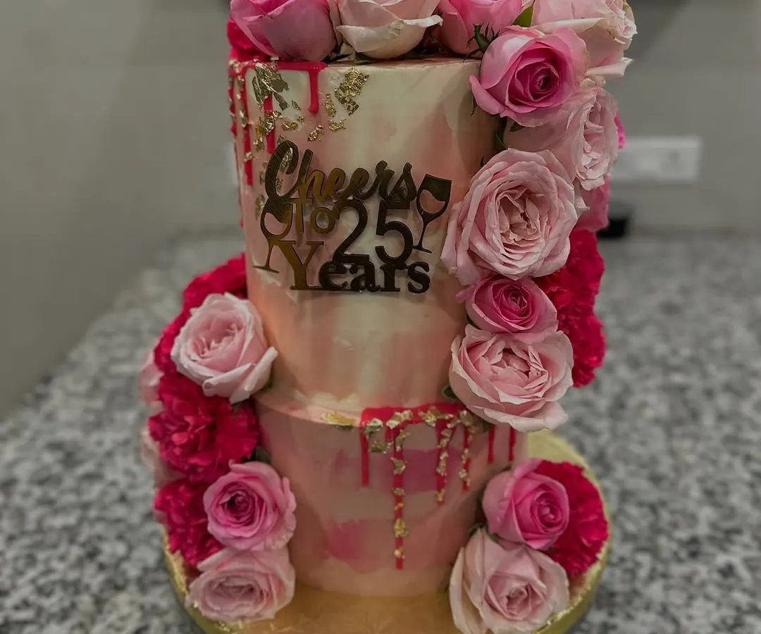 A two-tiered masterpiece for a 25th wedding anniversary, blending rich Belgian chocolate and refreshing Mango Vanilla flavors. The design features a cascade of fresh pink roses and delicate gold leaf for a touch of luxury.