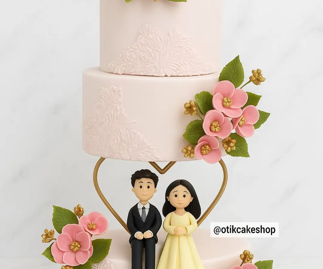 For a truly special union, we designed this elegant three-tiered wedding cake. Adorned with delicate pink sugar flowers and a custom couple figurine, it’s a beautiful centerpiece for celebrating love.