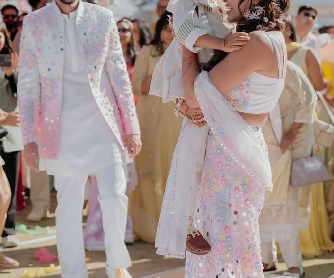 It is a special joy to dress an entire family. Here, we designed a coordinated set in white and pastels, with unique floral and mirror work on the father's jacket, the mother's lehenga saree, and the son's matching kurta, ensuring they looked united yet individual.