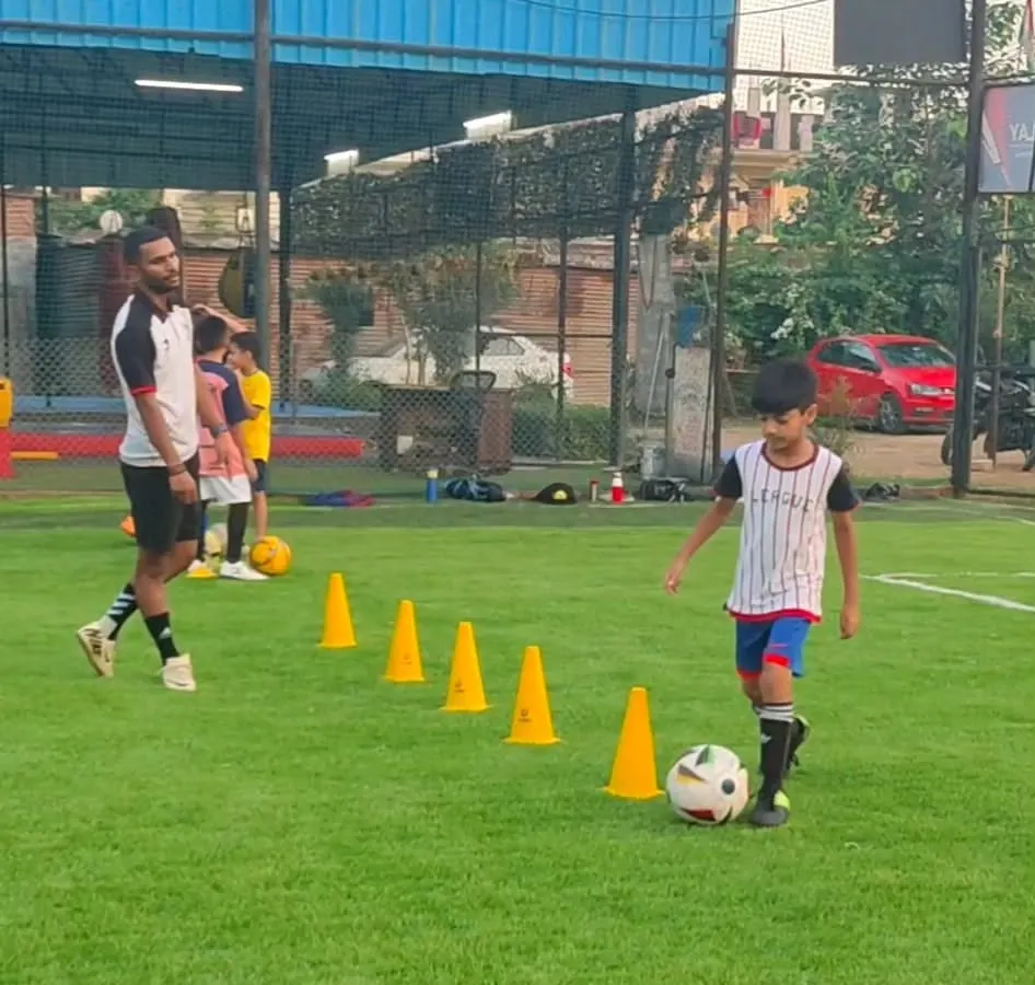 It all starts here, with one-on-one coaching and mastering the fundamentals. A coach guides a young player through a cone drill, focusing on ball control and agility.