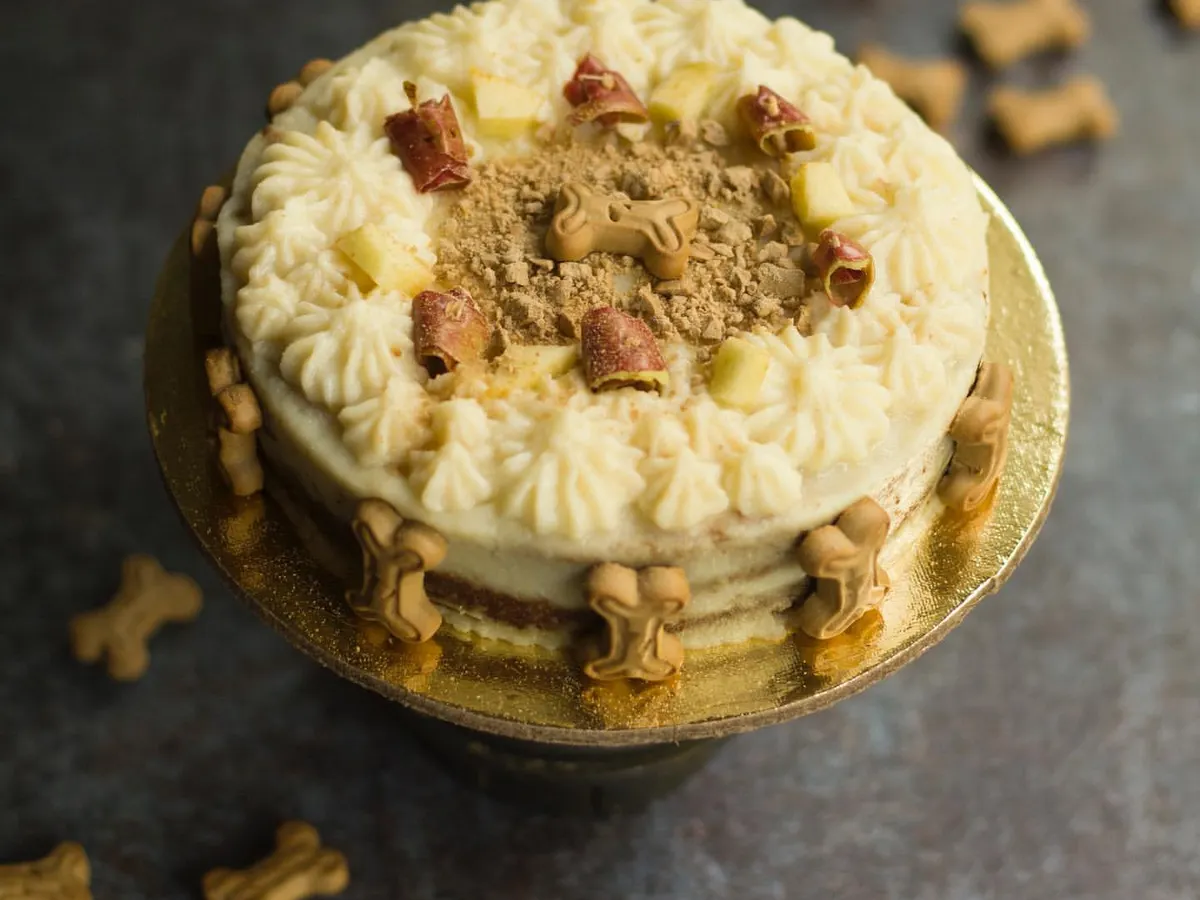 This is my super popular Apple and Peanutbutter cake, looking absolutely delicious! I decorate it with creamy frosting, crunchy dog biscuits, and fresh apple pieces. It's a healthy and beautiful centerpiece for any dog party.