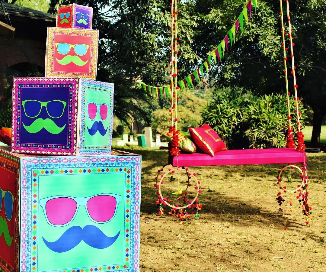 This outdoor Mehendi setup captures my signature style: bold, fun, and full of personality. I designed the custom graphic boxes and the decorated pink swing to create a vibrant, Instagram-worthy corner for the celebration, perfect for a daytime event.