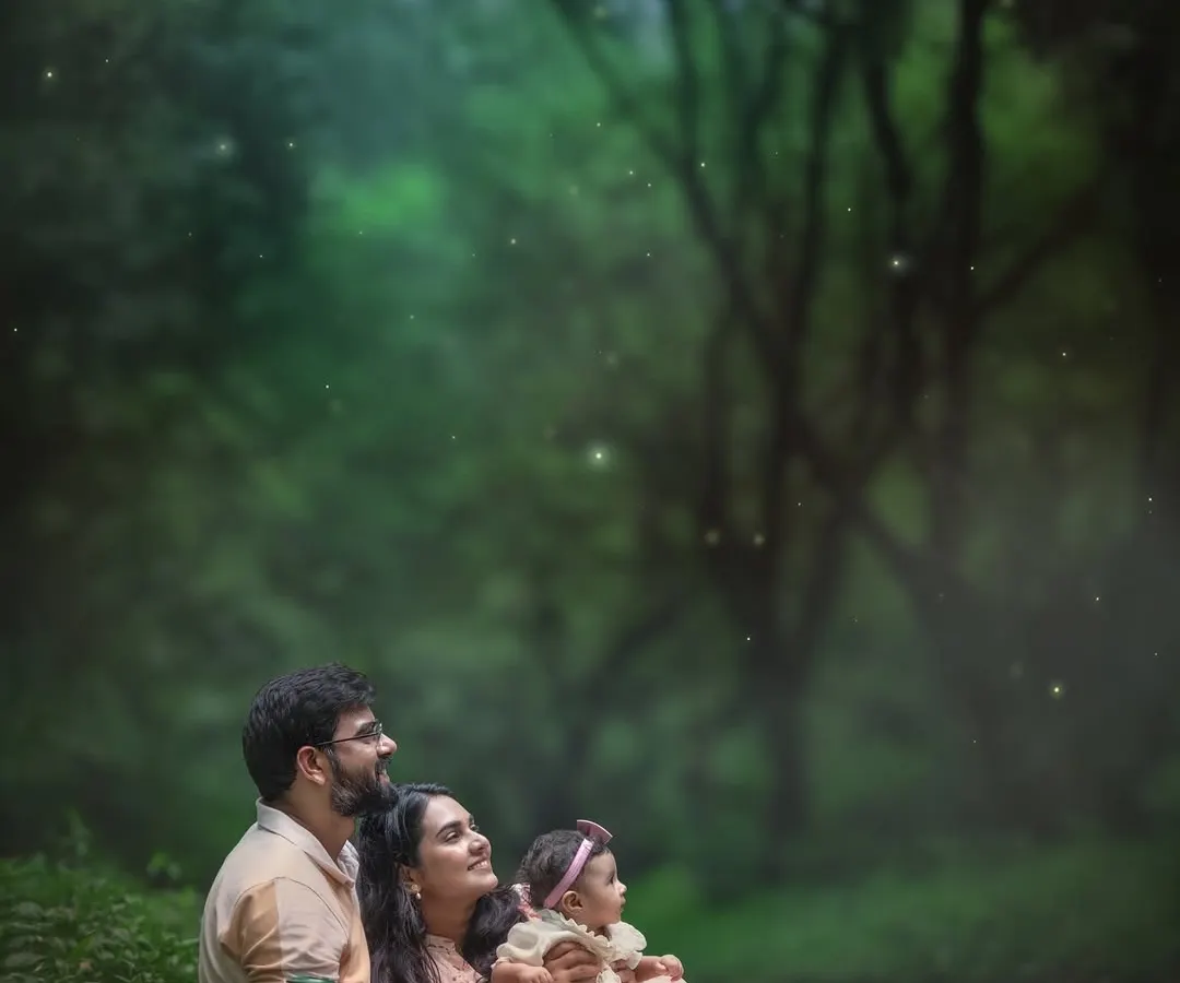 A family sitting together in the woods as dusk settles, with the warm glow of a lantern and a sprinkle of magical fireflies. This is more than a portrait; it’s a fairytale moment created just for them.