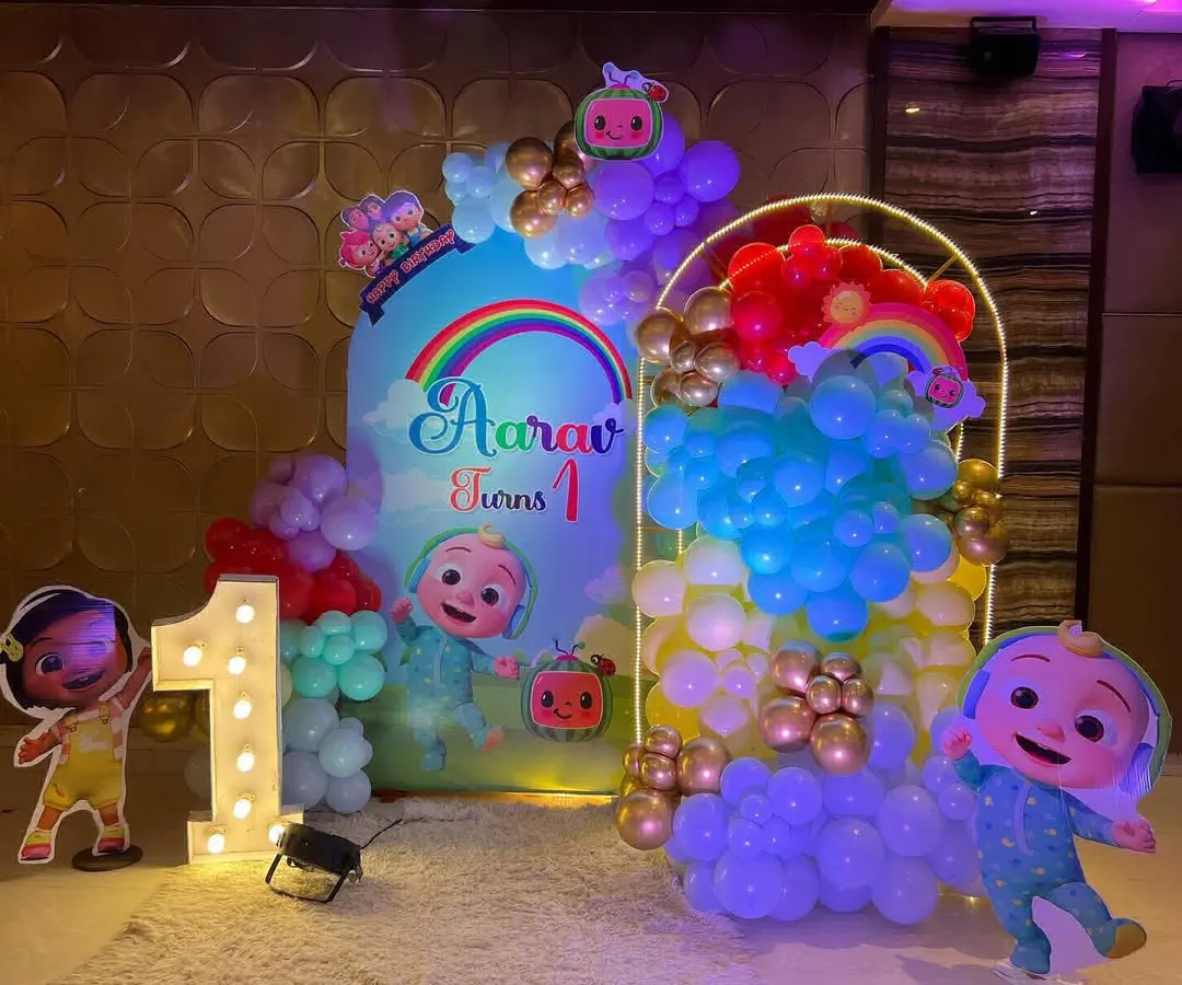 A complete Cocomelon theme for a first birthday, one of our most requested designs for toddlers. It features character cutouts of JJ and friends, a rainbow balloon arch, and a large light-up marquee number '1'.