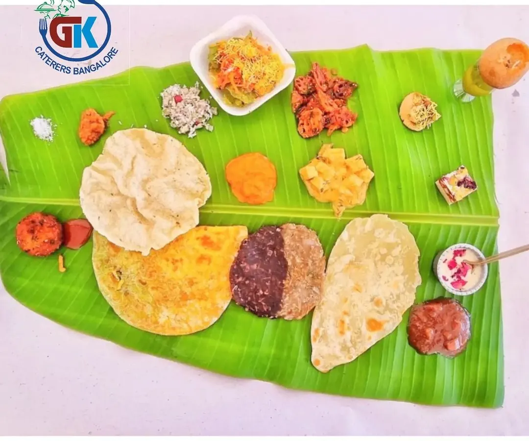 This is what a proper Karnataka wedding feast looks like on a banana leaf. You can see our special 50-50 Holige, a variety of palyas, kosambari, and crispy snacks. I make sure every oota is a grand and authentic experience.