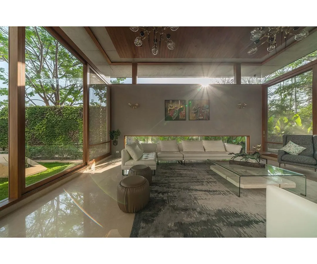 We designed this living room with a floating roof and expansive glass walls to create a space that feels boundless, inviting sunlight and the surrounding greenery indoors.