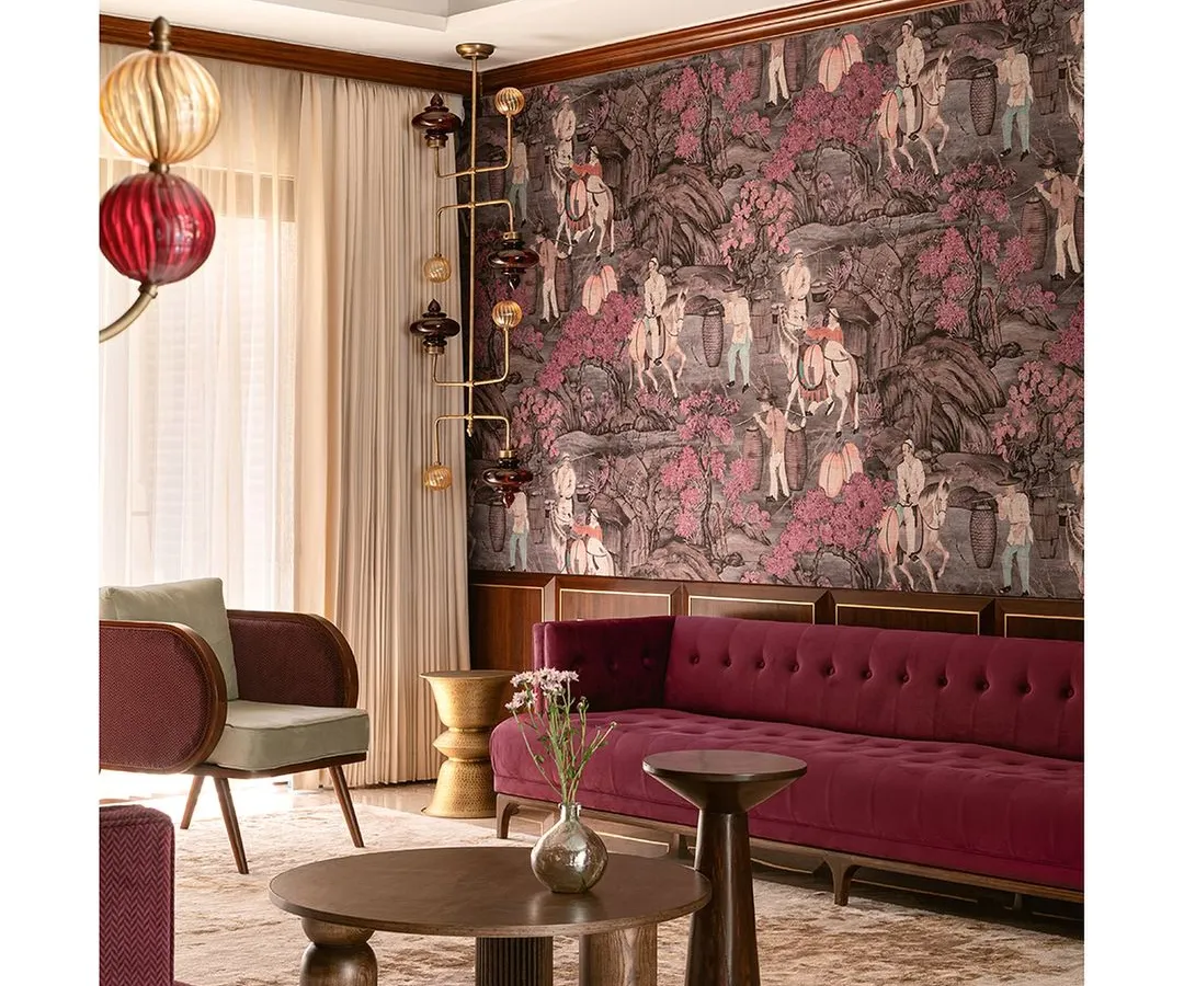 We love to weave a narrative of texture and layers, transforming a home into a vibrant, artful canvas. Here, a bold magenta velvet sofa and dramatic wallpaper create a symphony of color that redefines contemporary elegance and makes the formal living room a visual delight.