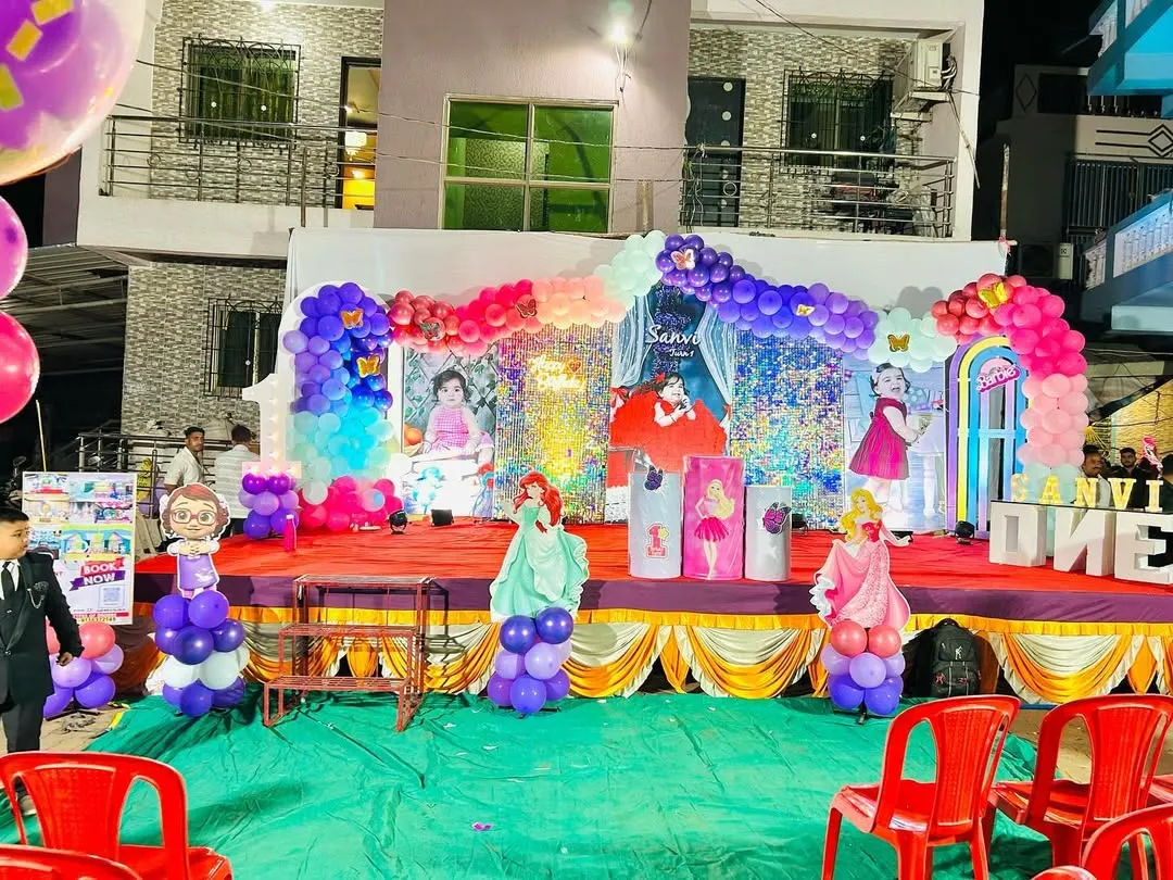 A full view of an outdoor princess-themed birthday party stage. I designed this setup with multiple character cutouts, a shimmering backdrop, and elaborate balloon garlands in pink, purple, and blue to create a magical kingdom for the birthday girl.
