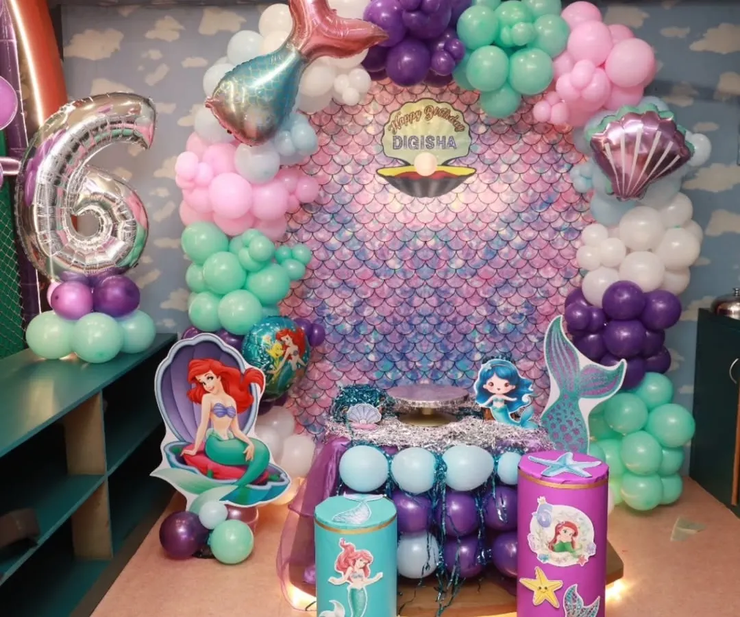 I believe in making dreams come true with magical themed parties. This stunning mermaid birthday setup, complete with an iridescent backdrop and under-the-sea balloon decor, shows how I transform my space into a fairy tale world for your child's special day.