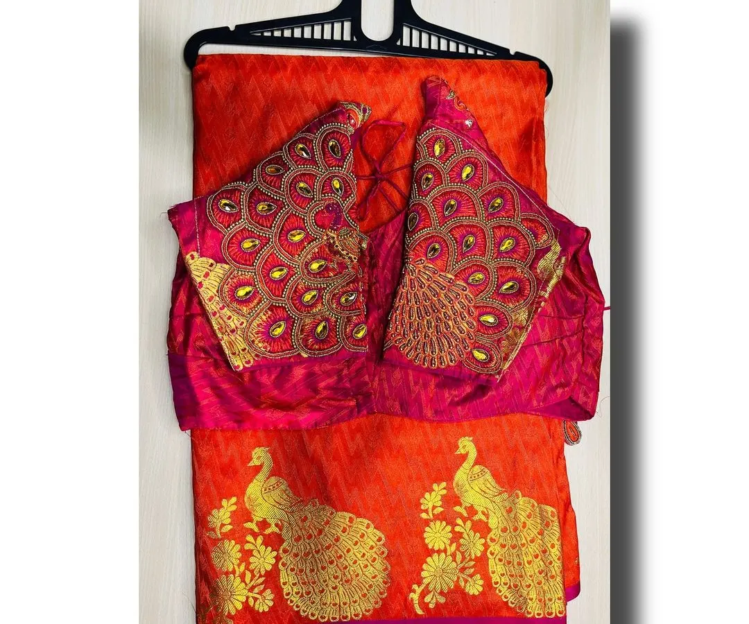 I offer a range of silk sarees with heavily embroidered designer blouses. This vibrant red saree comes with a matching blouse featuring an intricate peacock feather design on the sleeves, so you get a complete, ready-to-wear look.