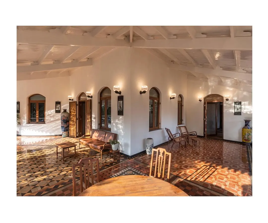 The restored veranda, where sunlight plays across the original geometric tile flooring. We focused on reviving these transitional spaces to create a seamless connection between the historic interiors and the natural surroundings, blending colonial and vernacular influences.
