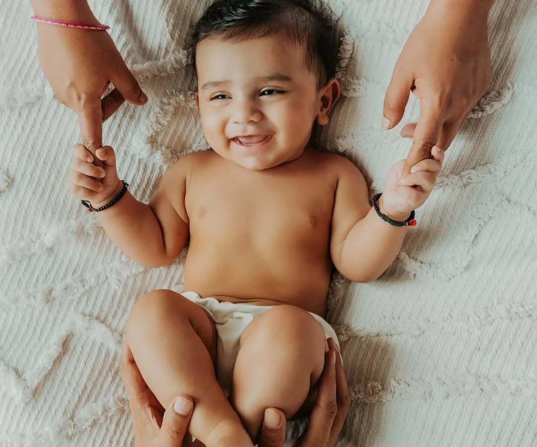 There is nothing more beautiful than a baby's smile. This moment, with mom and dad's hands holding their little one, captures the pure joy and connection that fills a new family. These are the simple, heartfelt memories I aim to preserve for you.
