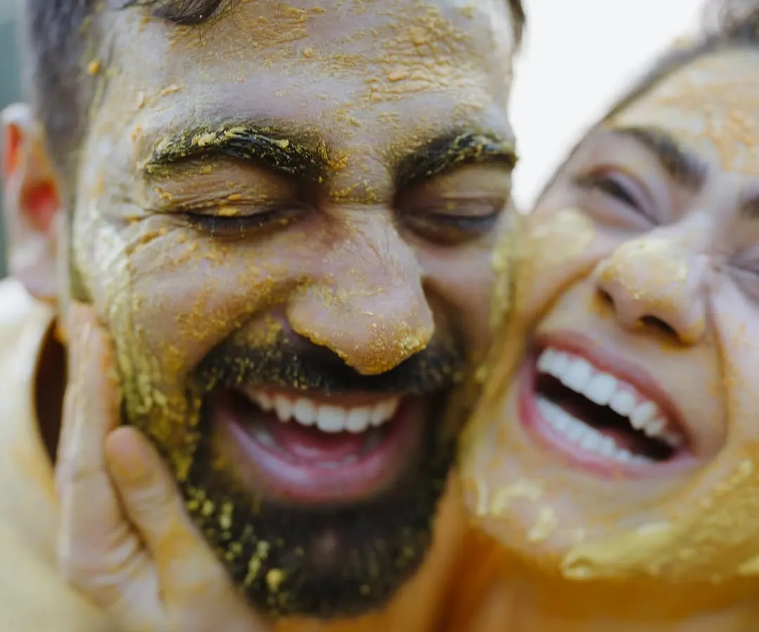 Pure, unadulterated joy. We believe the best moments are the unscripted ones, like this candid laugh during a Haldi ceremony, where love is smeared on with turmeric and happiness.