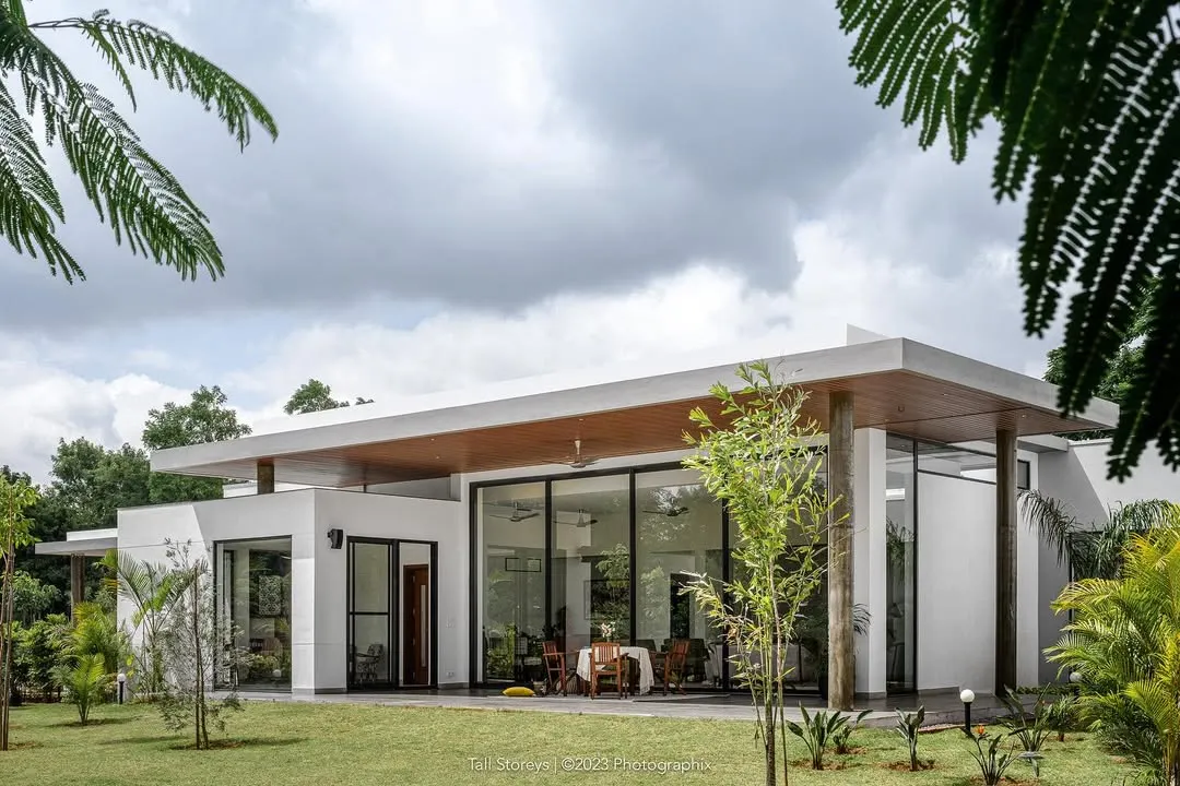 A view of our project, "Nisarg," a contemporary farmhouse near Bengaluru. The design blurs the line between indoors and outdoors, with expansive glass walls that open the living spaces to the garden and the forest beyond.
