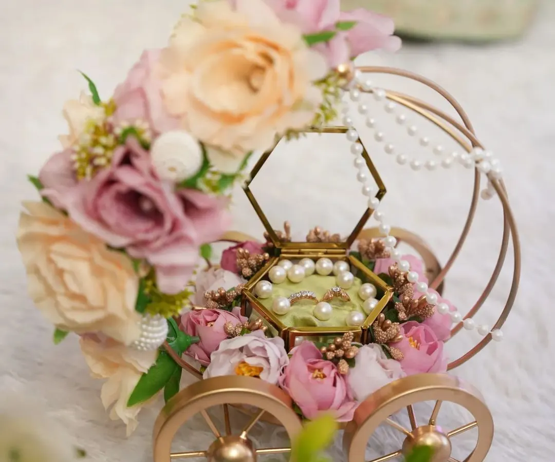 This isn't just a ring platter; it's a centerpiece. Our "Ring on Wheels" carriage, adorned with pastel florals and delicate pearls, makes the ring exchange ceremony truly magical and unforgettable.