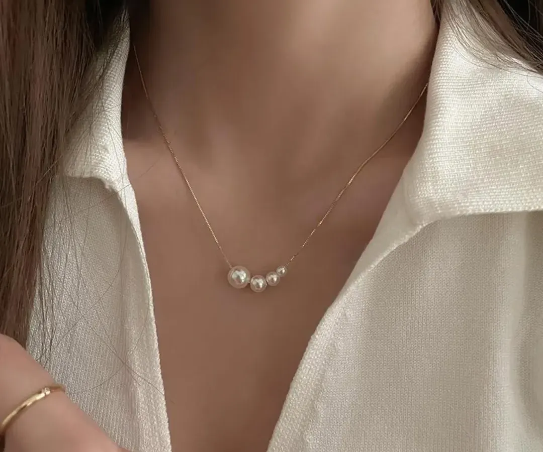 A simple and classic piece for everyday elegance. This delicate necklace features a series of graduating pearls on a fine, gold-tone stainless steel chain, perfect for wearing to university or work.