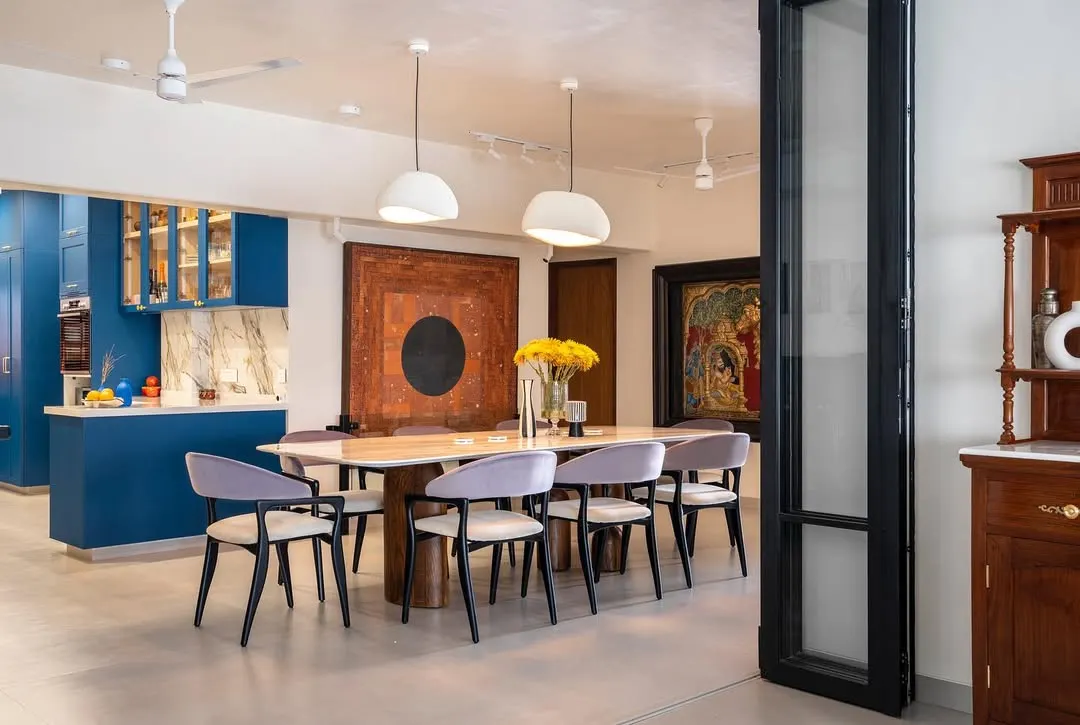 We believe in using color with confidence. In this open-plan Vile Parle apartment, a bold blue kitchen becomes the vibrant heart of the home, seamlessly connecting to the dining area. The custom dining table and chairs, along with striking artwork, create a space perfect for entertaining.