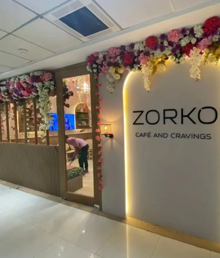 An elegant artificial floral installation framing the entrance of Zorko Cafe. This type of long-lasting decor is perfect for creating a sophisticated first impression for cafes, salons, and boutiques.