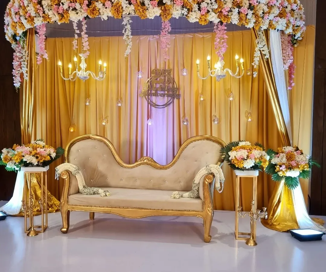 A classic and elegant stage for a 25th wedding anniversary. I used gold drapery, crystal chandeliers, and lush floral arrangements to create a royal look, complete with a vintage-style chaise lounge for photos.
