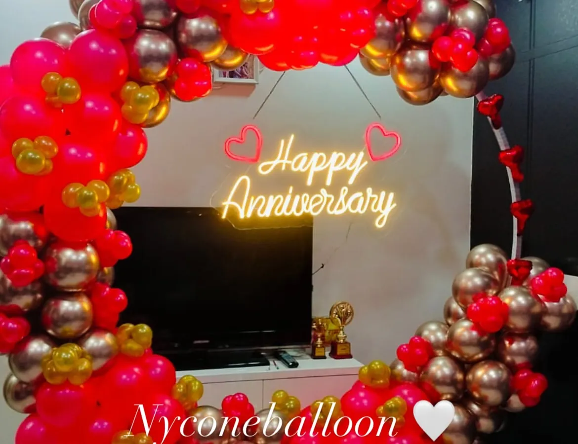 For a modern and stylish celebration, I create these circular balloon backdrops. This one uses a vibrant mix of pink and gold balloons and features a bright 'Happy Anniversary' neon sign, perfect for taking memorable photos.