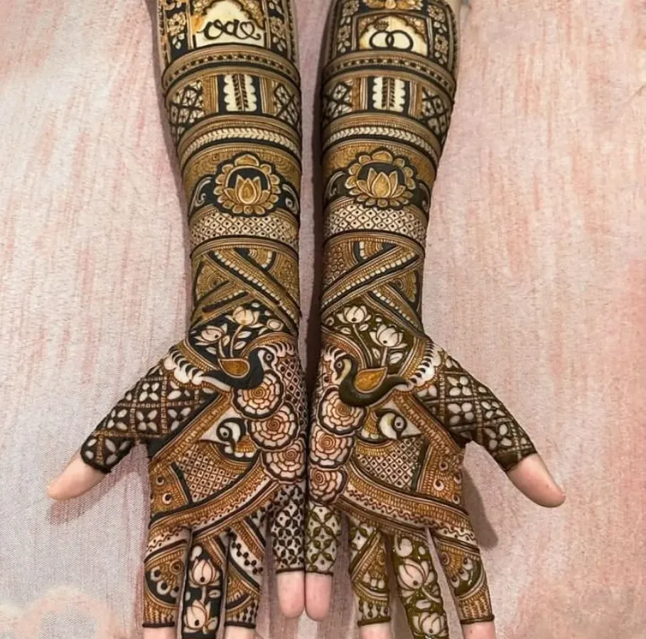 Symmetry and sharpness are obsessions for me. This full-arm bridal mehendi features perfectly mirrored peacocks and architectural jharokha patterns, showing the 'baariki' or fine detailing that I am known for.