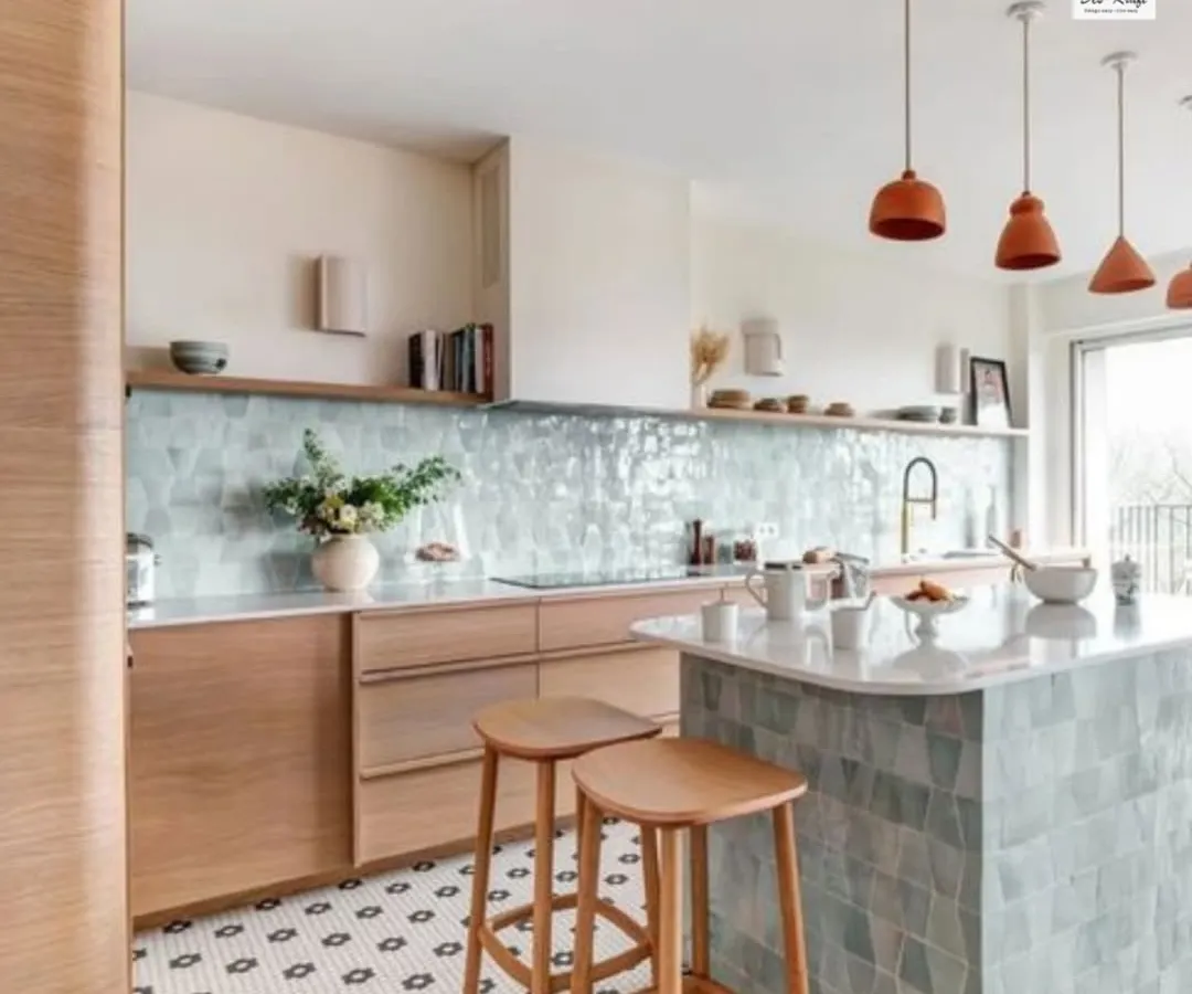 We believe a kitchen should be both beautiful and highly functional. This modern kitchen design features a stunning pastel blue tile backsplash, a versatile island with bar seating, and natural wood cabinetry, creating a bright and airy atmosphere for cooking and gathering.