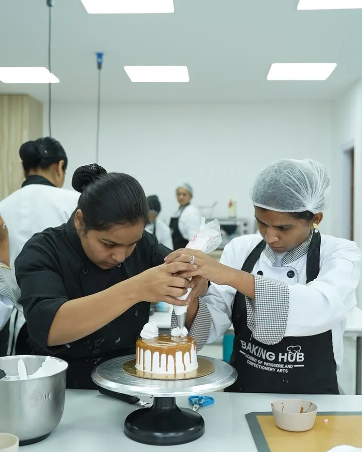 We believe in 100% hands-on learning. Here, I am guiding a student to perfect her piping technique on a caramel drip cake. You get personal attention to ensure you master every skill, from holding the piping bag correctly to creating beautiful, stable decorations.