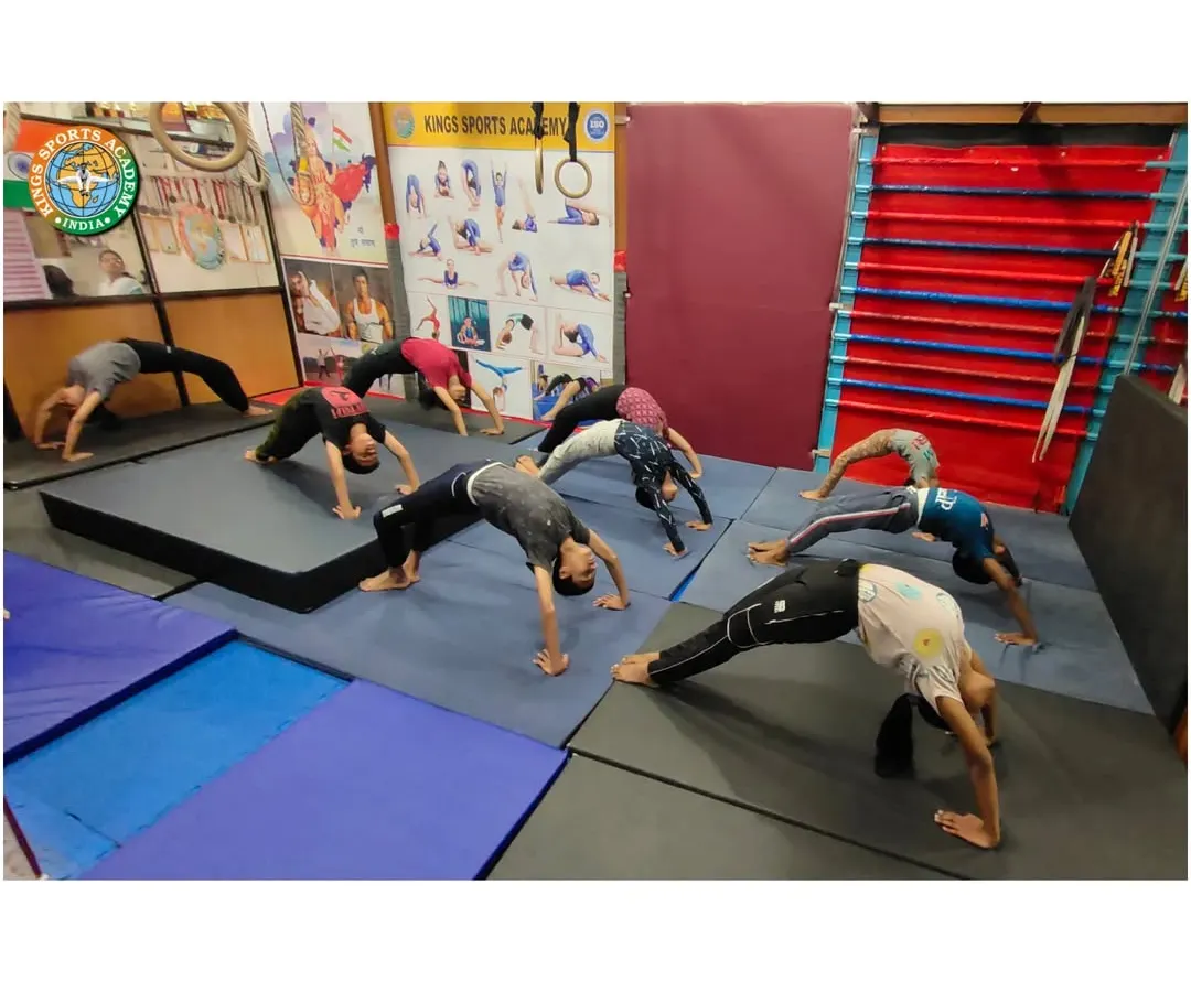 A look inside our group classes where students work on flexibility and back strength. Here, a group practices Chakrasana, or the wheel pose, on padded mats, showing the focused and disciplined environment of our academy.