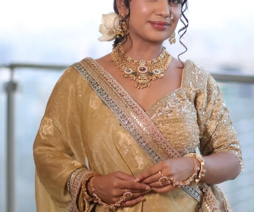 A full view of a timeless bridal look in golden hues. This showcases not just the makeup, but also the complete styling with hair and lehenga draping to create an elegant and cohesive appearance.