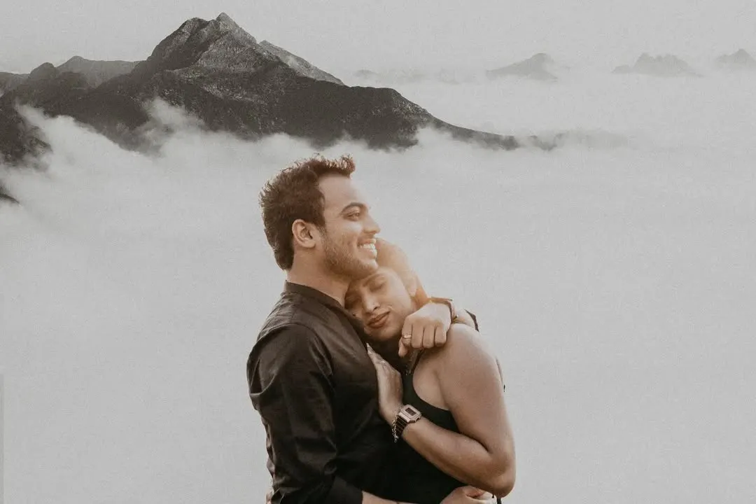 Above a sea of clouds on a misty mountain, this couple's embrace feels like the only thing in the world. This black and white portrait focuses purely on the serene, powerful emotion of their bond during their outdoor couple photoshoot.