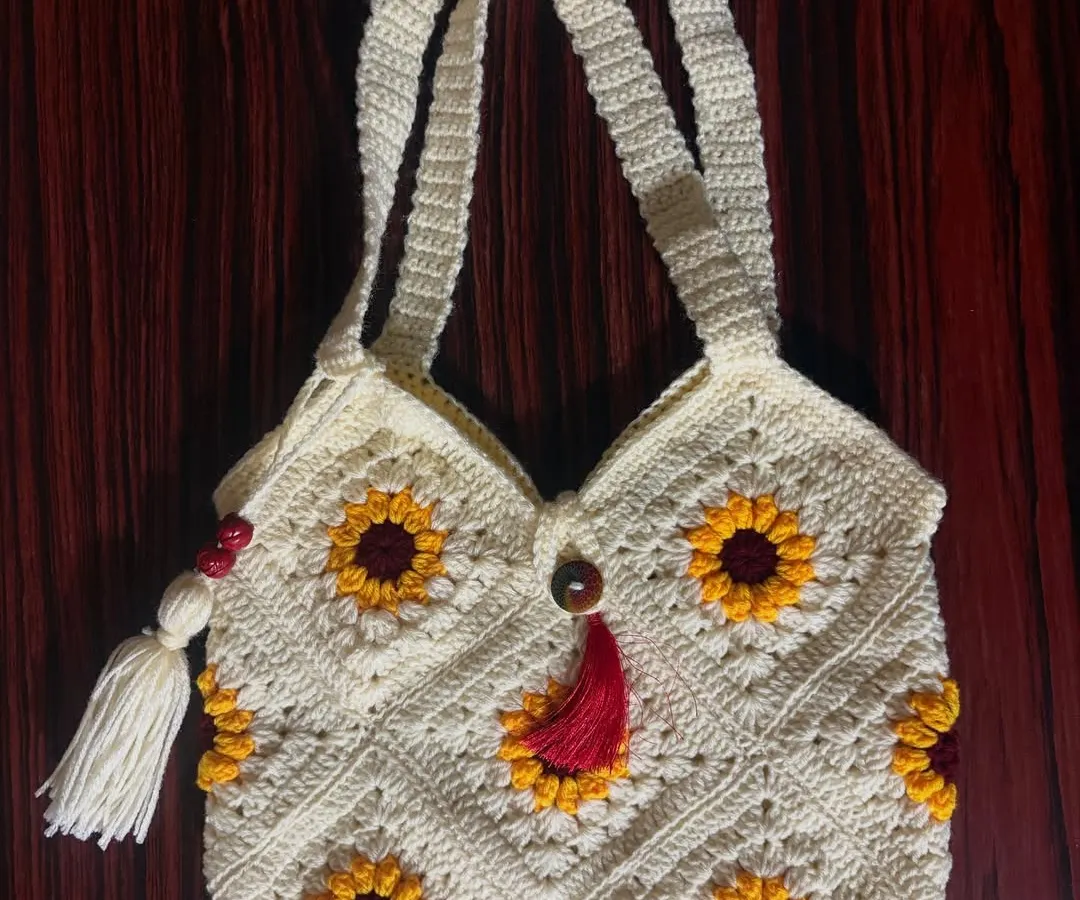 My granny square tote bag, featuring a cheerful sunflower pattern and decorative tassels, is a perfect blend of bohemian style and practical design for everyday use.