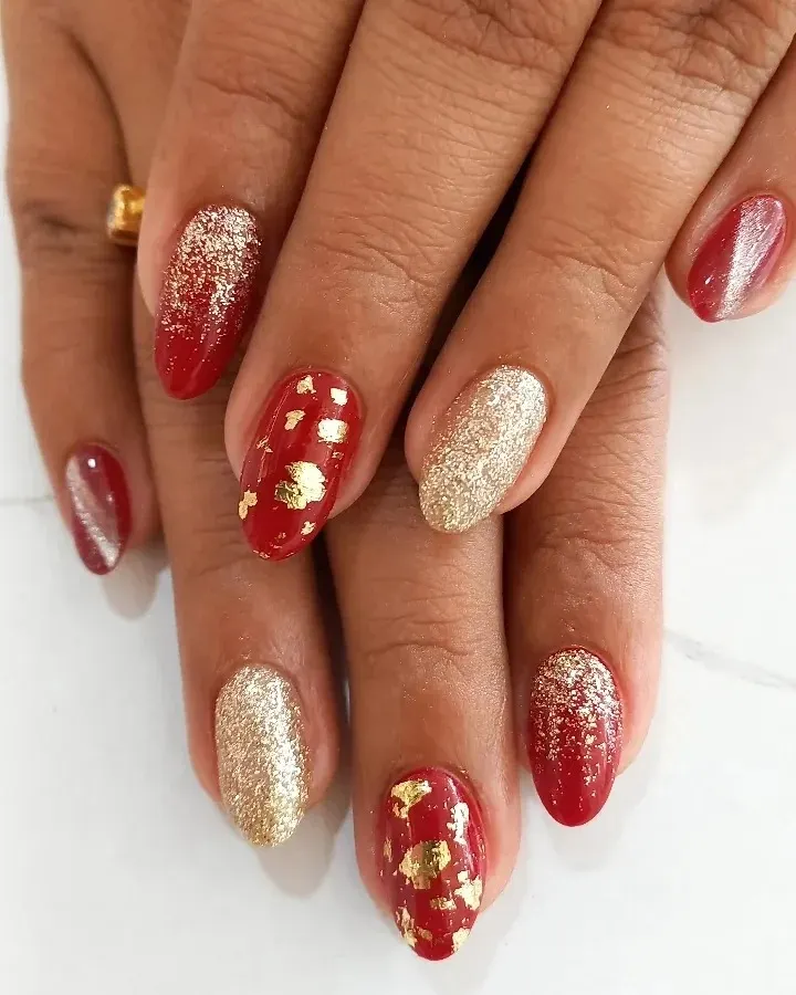 Perfect for celebrations, this festive manicure combines a rich red base with accent nails in full-coverage gold glitter and delicate gold foil flakes. This is a popular choice for bridal parties and holiday events.