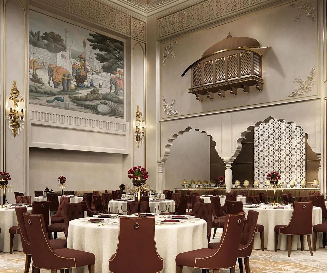 We believe luxury is in the details. This view of a grand banquet hall interior showcases our blend of Rajasthani and Islamic architectural elements, featuring a traditional jharokha, custom maroon seating, and intricate wall murals to create a regal atmosphere for any celebration.