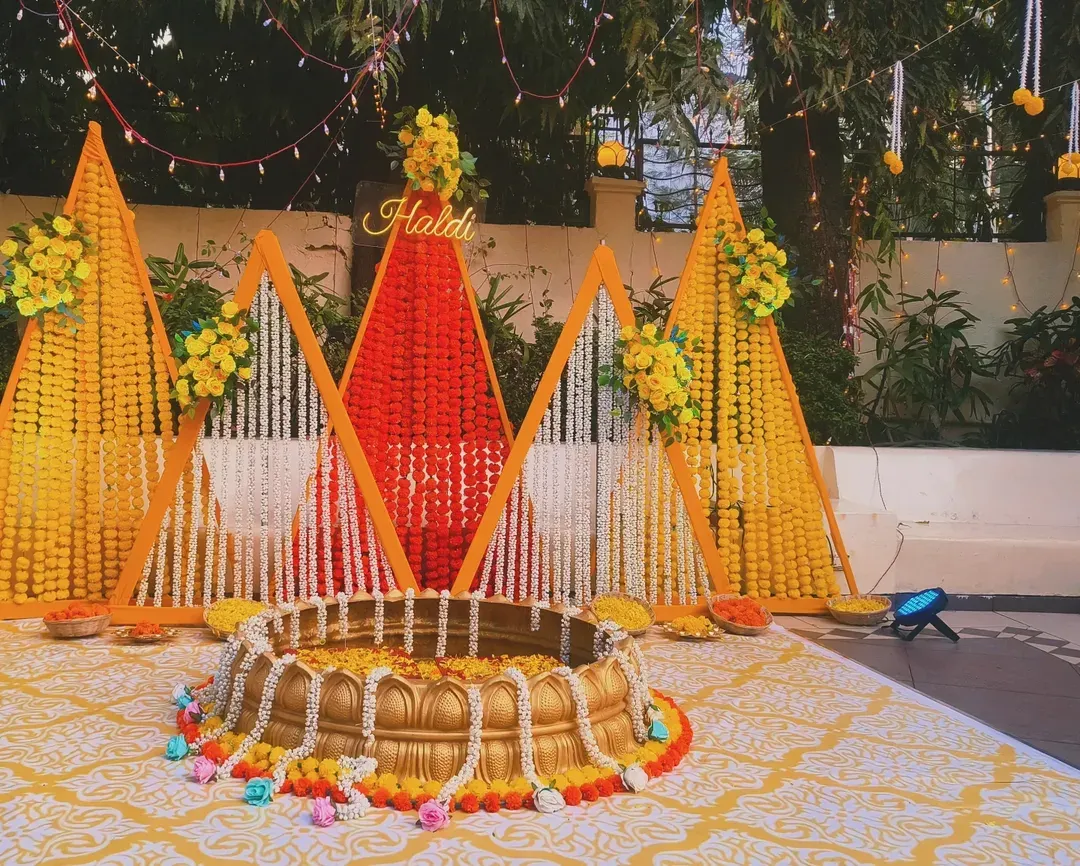 For a vibrant outdoor haldi ceremony, I designed this modern setup using geometric panels of marigold and jasmine flowers, centered around a traditional urli for the rituals.