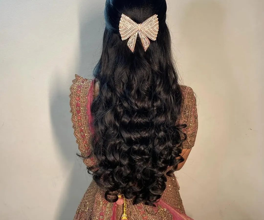 For a glamorous reception, I styled this client's hair in voluminous, bouncy curls. The look is completed with a modern, sparkling bow clip, creating a half-updo that is perfect for dancing the night away.