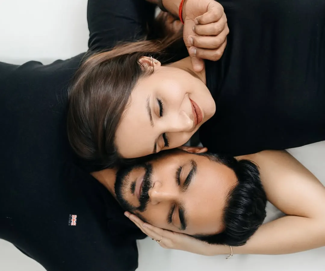 This overhead portrait from a minimalist indoor session highlights the couple's closeness. Shot against a simple white backdrop, the focus is entirely on their serene expressions and intimate connection, creating a timeless and artistic piece of their love story.
