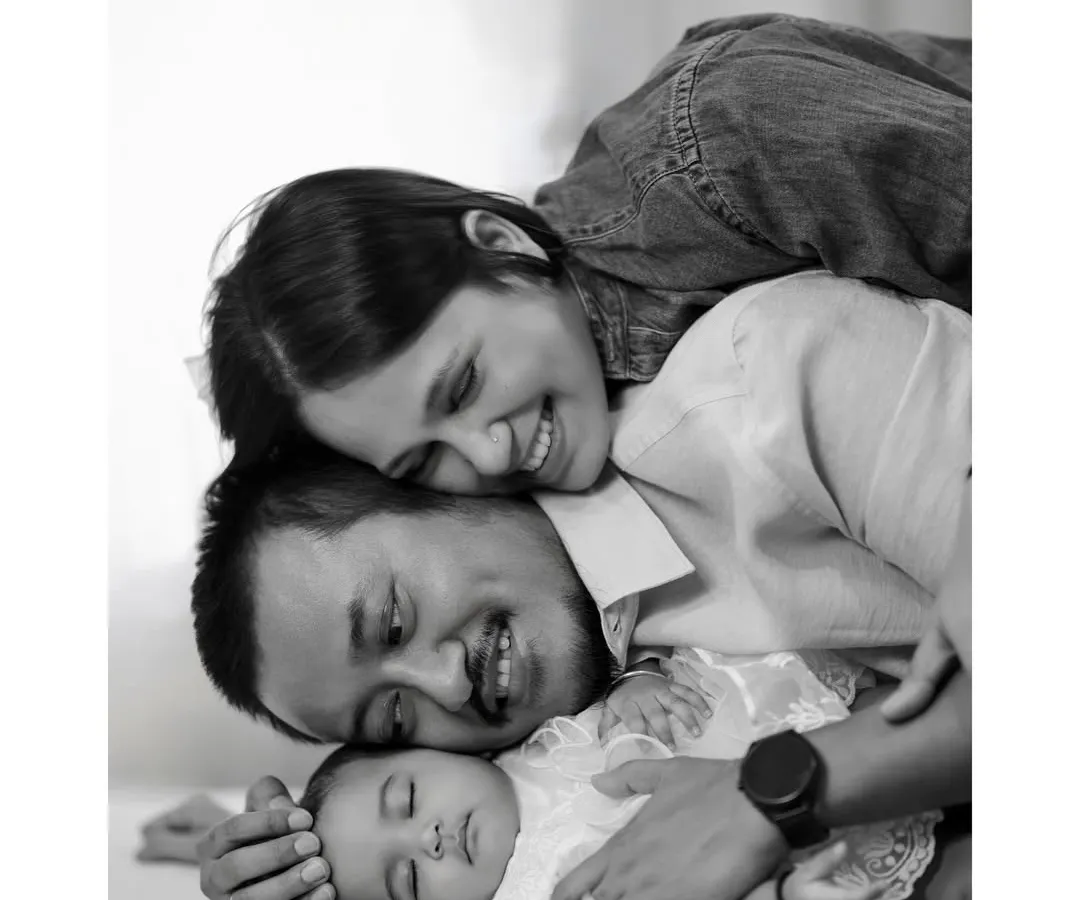 In the quiet moments, love speaks the loudest. This classic black and white portrait captures the profound bond between new parents and their sleeping baby, a memory to hold forever.