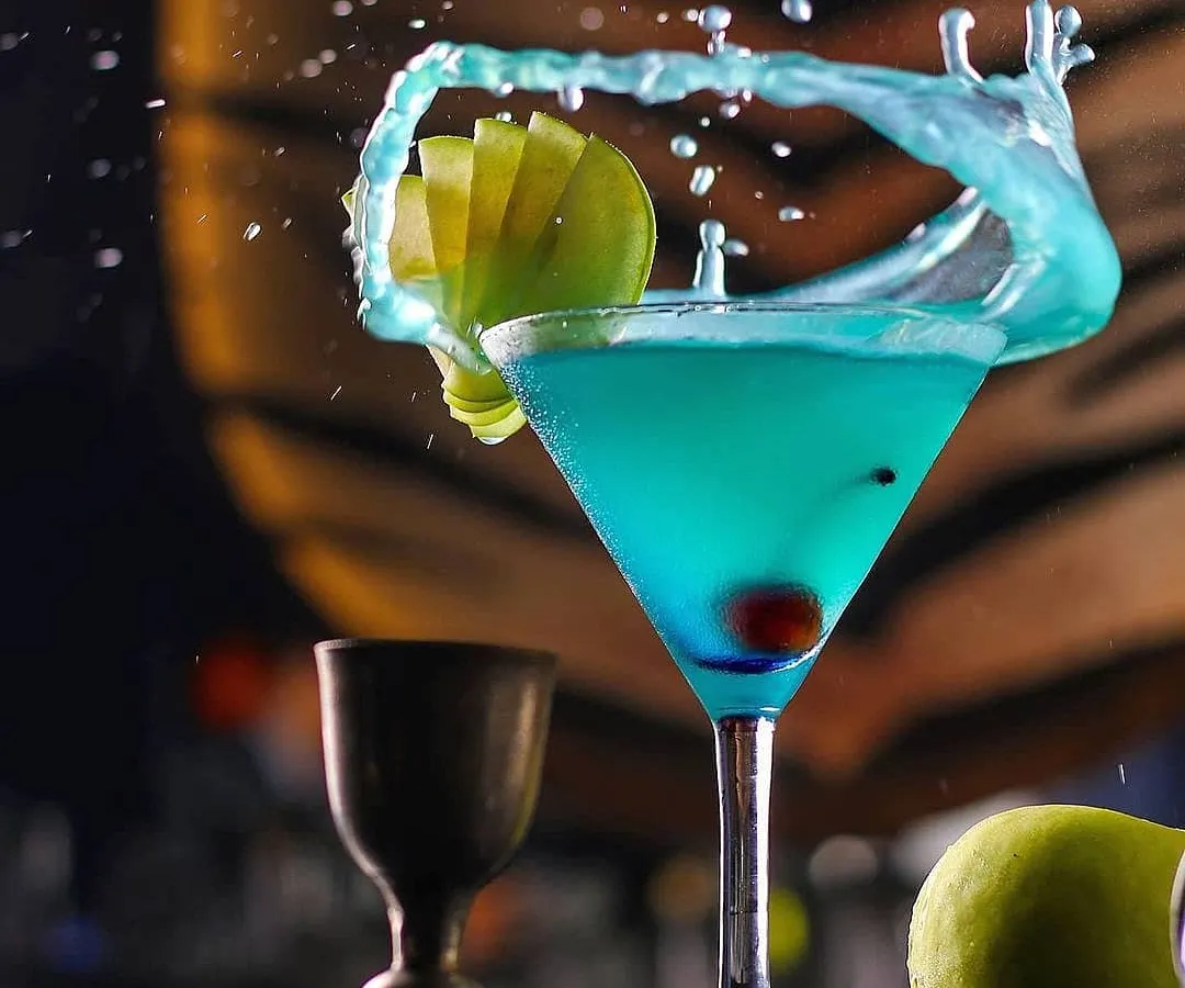 A dynamic splash shot of a blue cocktail, demonstrating the technical skill our commercial photographers use to create eye-catching imagery for bars, restaurants, and beverage brands.