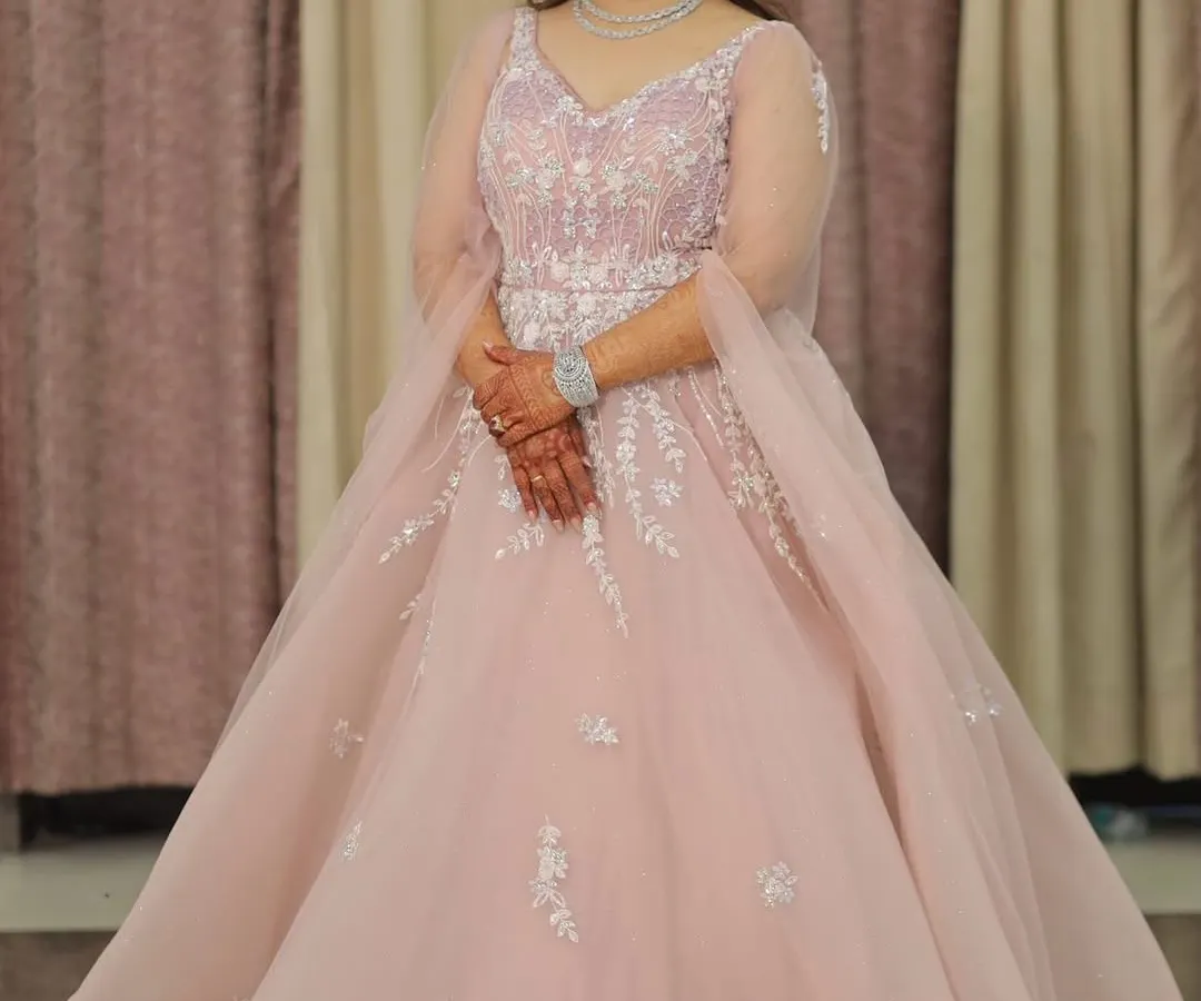 Feel like a princess in this beautiful pastel pink ball gown. With delicate silver embroidery on the bodice and sheer sleeves, this rental gown is a fantastic choice for an engagement, reception, or a pre-wedding photoshoot.