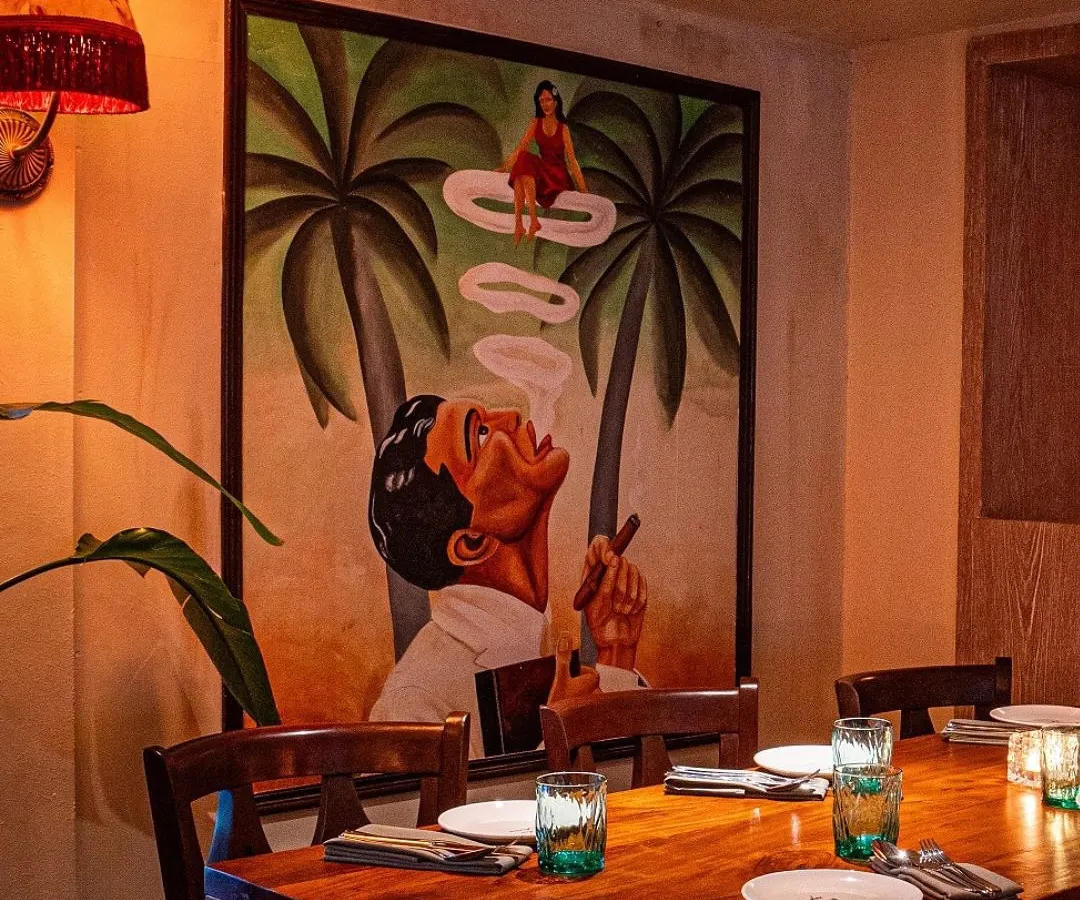 We love creating a specific mood with our art. This surreal painting, featuring a woman appearing in a puff of smoke, sets a cool, imaginative vibe for the dining area at Maze Concept.