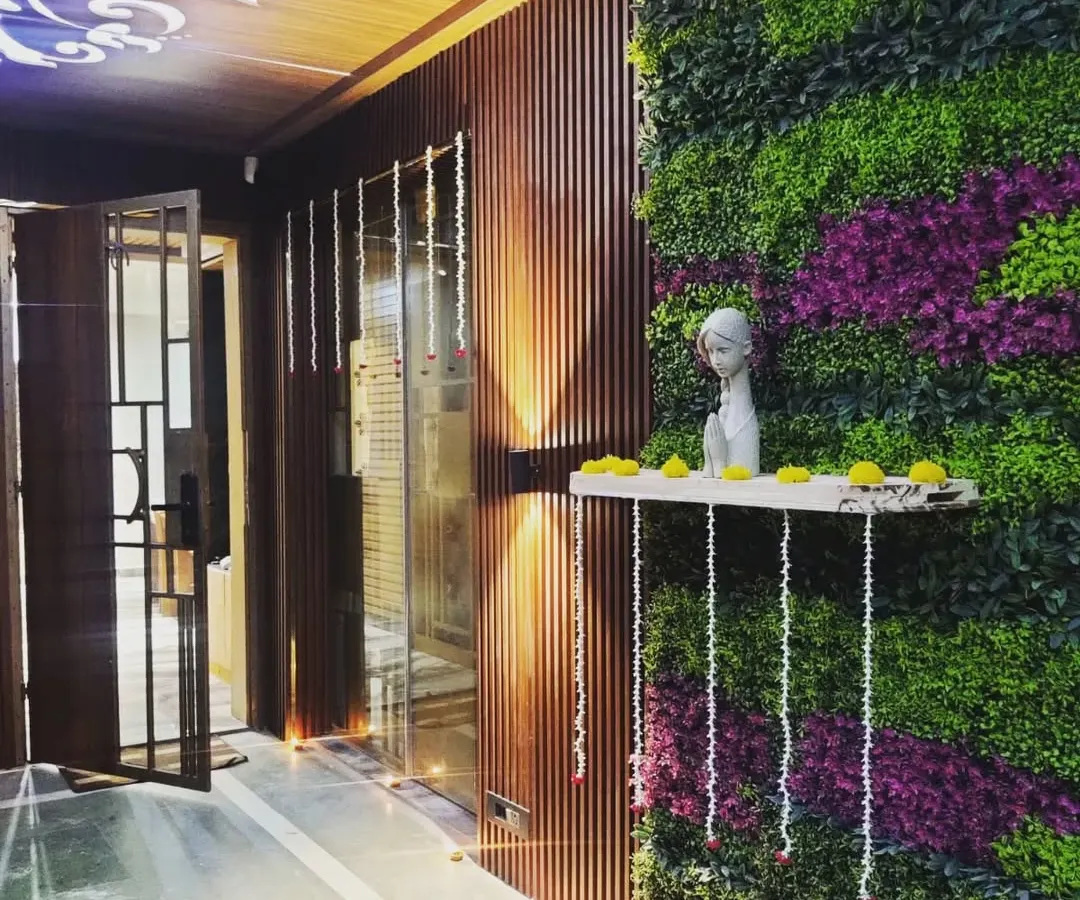 We designed this elegant entryway to welcome residents home with a touch of nature. The combination of a lush vertical garden with purple accents, warm wood louvers, and soft up-lighting creates a sophisticated and serene first impression.