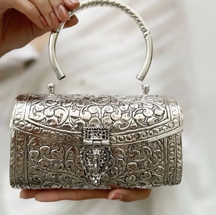 I believe accessories should be timeless works of art. This intricately carved German silver clutch is a statement of pure elegance, perfect for weddings and festive evenings. It is handcrafted to be an heirloom piece you will treasure forever.