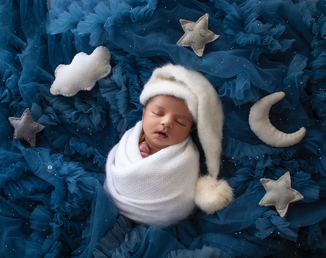 A peaceful newborn dreaming amongst the stars. My celestial-themed sessions use soft fabrics and props to create a magical, sleepy setting for your little one's first portraits.