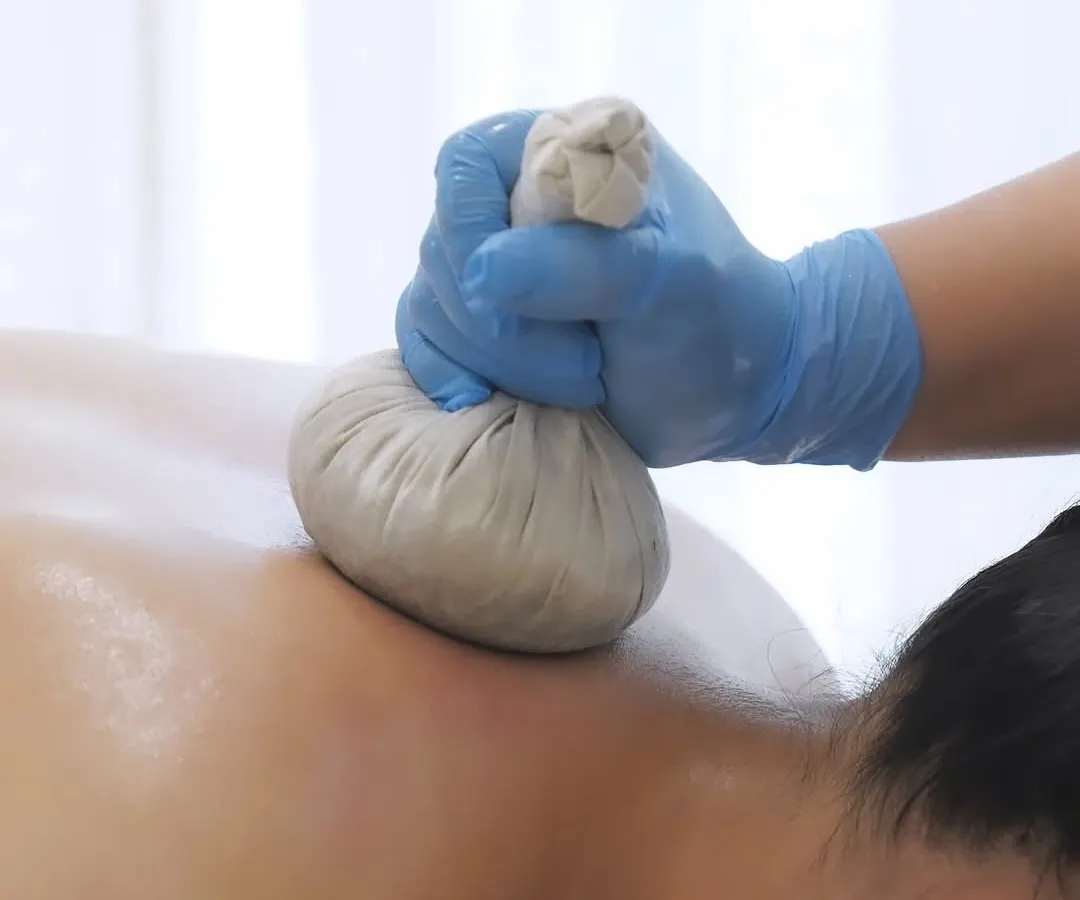 Discover the ancient healing of our Potli massage. This close-up shows a heated herbal pouch, packed with natural herbs, being pressed onto the skin to alleviate pain, reduce stiffness, and promote a sense of well-being.
